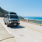 van crossing bridge over body of water