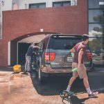 man cleaning silver SUV